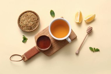 Sarı zemin üzerinde limon, nane ve bal ile bir fincan sıcak karabuğday çayı.