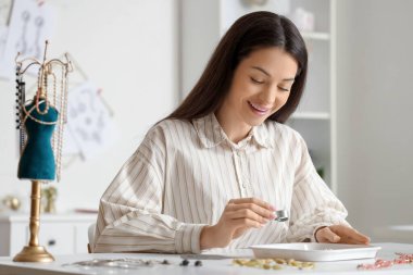 Kadın mücevher tasarımcısı atölyede mücevherleri inceliyor.