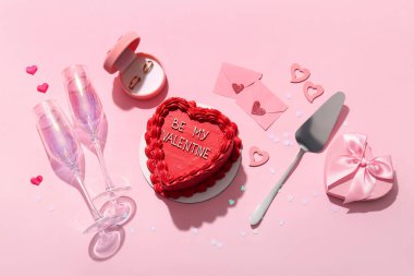 Hediye kutusu, nişan yüzükleri, zarflar ve pembe arka planda şampanya bardakları olan tatlı bento pastası. Sevgililer Günü kutlaması