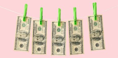 Çamaşır ipinde pembe arka planda asılı duran dolar banknotları. Para aklama kavramı