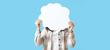 Açık mavi arka planda boş konuşma balonu olan genç bir kadın.