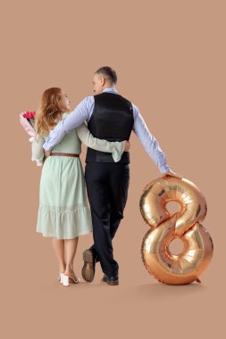 Bej arka planda, balon ve buketi olan orta yaşlı bir çift. Uluslararası Kadınlar Günü