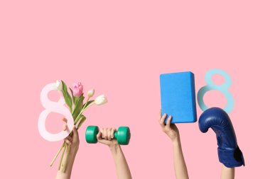 Spor malzemeli kadın eller, kağıt rakamları 8 ve pembe arka planda Uluslararası Kadınlar Günü için lale çiçekleri