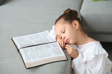 Evdeki kanepede İncil okuyan tatlı küçük kız.