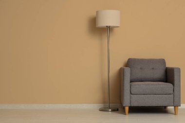 Koltuk ve yer lambası Bej duvarın yanında