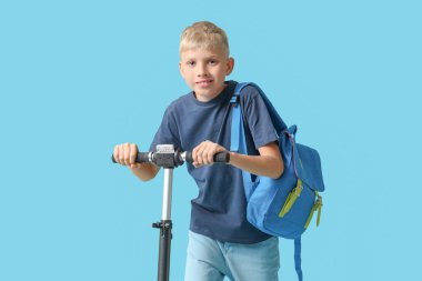 Modern elektrikli scooter 'ı ve mavi arka planda sırt çantası olan tatlı bir okul çocuğu.