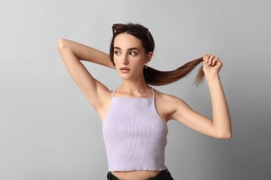 Gri arka planda şık güneş gözlüklü güzel bir genç kadın.