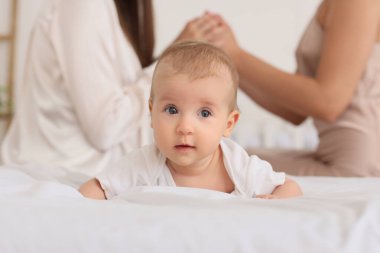 Yatak odasındaki lezbiyen çifte karşı yatakta tatlı bir bebek, yakın plan.