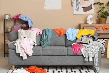 Gri kanepesi ve dağınık kıyafetleri olan dağınık bir oturma odası.