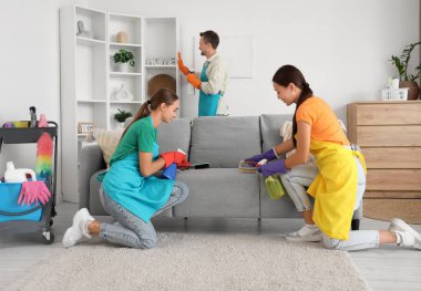 Odadaki kanepeyi temizleyen kadın hademeler.