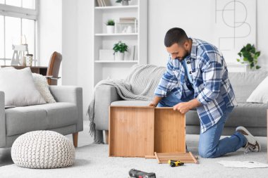 Young man assembling table with drawer at home