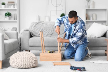 Young man assembling table at home