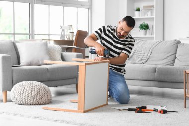 Evinde eğitim masası olan genç bir adam.