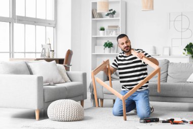 Young man assembling table at home