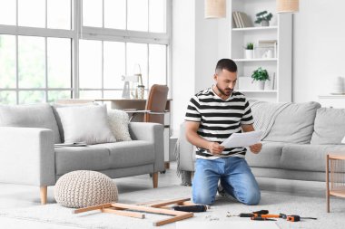 Young man with manual assembling table at home