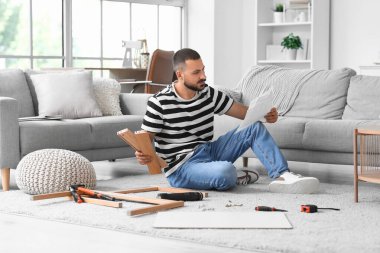 Talimatları evde toplayan genç adam.