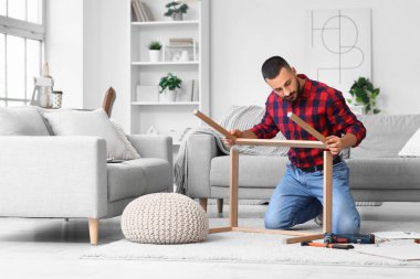 Young man assembling table at home