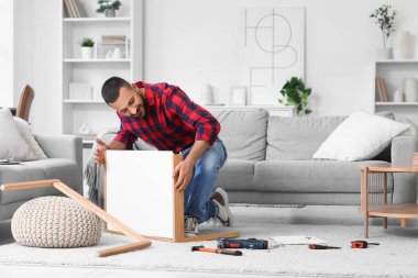 Young man assembling table at home