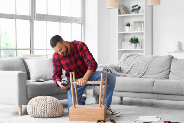 Evinde ahşap masa montajı yapan genç bir adam.