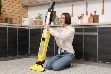 Mutfakta modern elektrik süpürgesi olan güzel genç bir kadın.