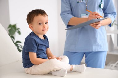 Kanepede tatlı küçük bir çocuk klinikteki çocuk doktorunu ziyaret ediyor.