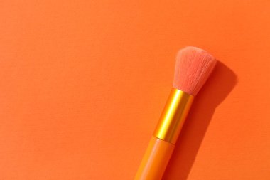 Turuncu arkaplanda makyaj fırçası, yakın plan