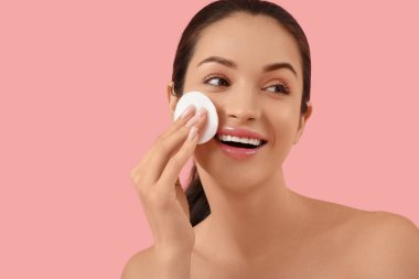 Pembe arka planda pamuk pedi olan güzel, mutlu genç bir kadın.