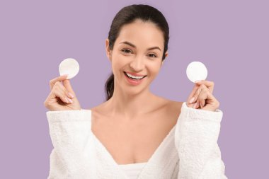 Bornozlu, mor arka planda pamuk yastıklı güzel, genç bir kadın.