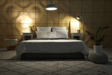 Masaları, çalar saati ve parlayan lambaları olan karanlık yatak odasının içi.