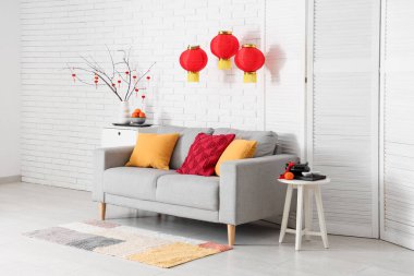 Çin Yeni Yılı için dekore edilmiş oturma odasının içi kanepe, masa ve katlanır ekran ile süslenmiş.