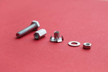 Kırmızı arka planda musluk cıvatası ve farklı krom fındıklar