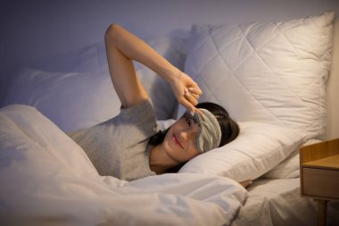 Güzel, genç, mutlu bir kadın. Maskeli bir kadın. Akşam yatağında yatıyor.