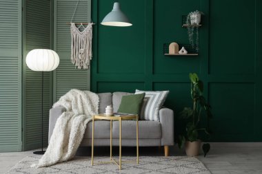 Oturma odasının içinde gri kanepe, katlanır perde ve parlayan lambalar.