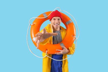 Male sailor with rescue ring on blue background clipart