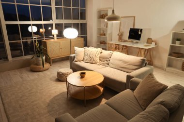 Gri koltukları, çekmeceleri ve parlak lambaları olan oturma odasının içinde.