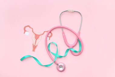 Kağıt uteruslu turkuaz kurdele ve pembe arka planda steteskop. Rahim Sağlığı Bilinci Ayı