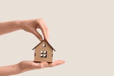 Beyaz arka planda ahşap oyuncak evi olan eller. Kira kavramı
