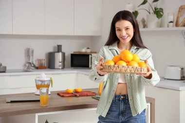 Mutfakta olgun portakalları olan genç bir kadın.