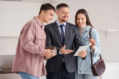 Tablet bilgisayarı olan bir emlakçı ve mutfakta bir çift.