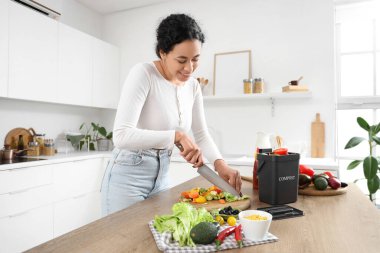 Genç Afro-Amerikalı kadın mutfaktaki gübre için sebze kesiyor.