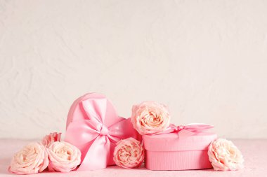 Beyaz arka planda hediye kutuları olan güller. Sevgililer Günü kutlaması