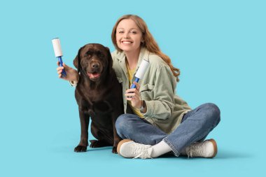 Tiftik silindirli ve labrador köpeği olan genç bir kadın mavi arka planda oturuyor.