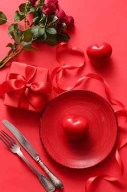 Kırmızı arka planda sevgililer günü için gül ve hediyeli güzel bir masa.