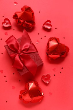 Kalp şeklinde balonları ve kırmızı arka planda mumları olan bir hediye kutusu. Sevgililer Günü kutlaması