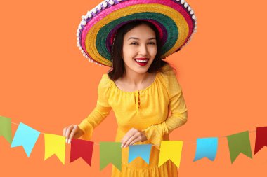 Meksika şapkalı mutlu genç kadın ve turuncu arka planda şenlikli çelenk