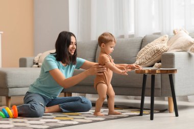 Küçük kız annesiyle evde yürümeyi öğreniyor.