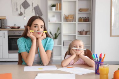 Dadı ve komik küçük kız mutfakta kalemler çiziyor.