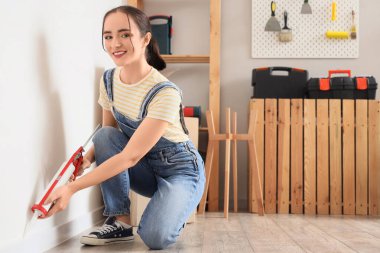 Odadaki duvara dolgu macunu süren genç bir kadın.