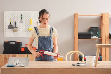 Masasında dolgu macunu olan genç bir kadın var.