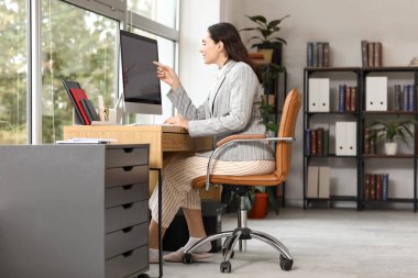 Ofiste bilgisayarla çalışan genç bir iş kadını. Ulusal İş Günü Pijamalarınızı Giyin